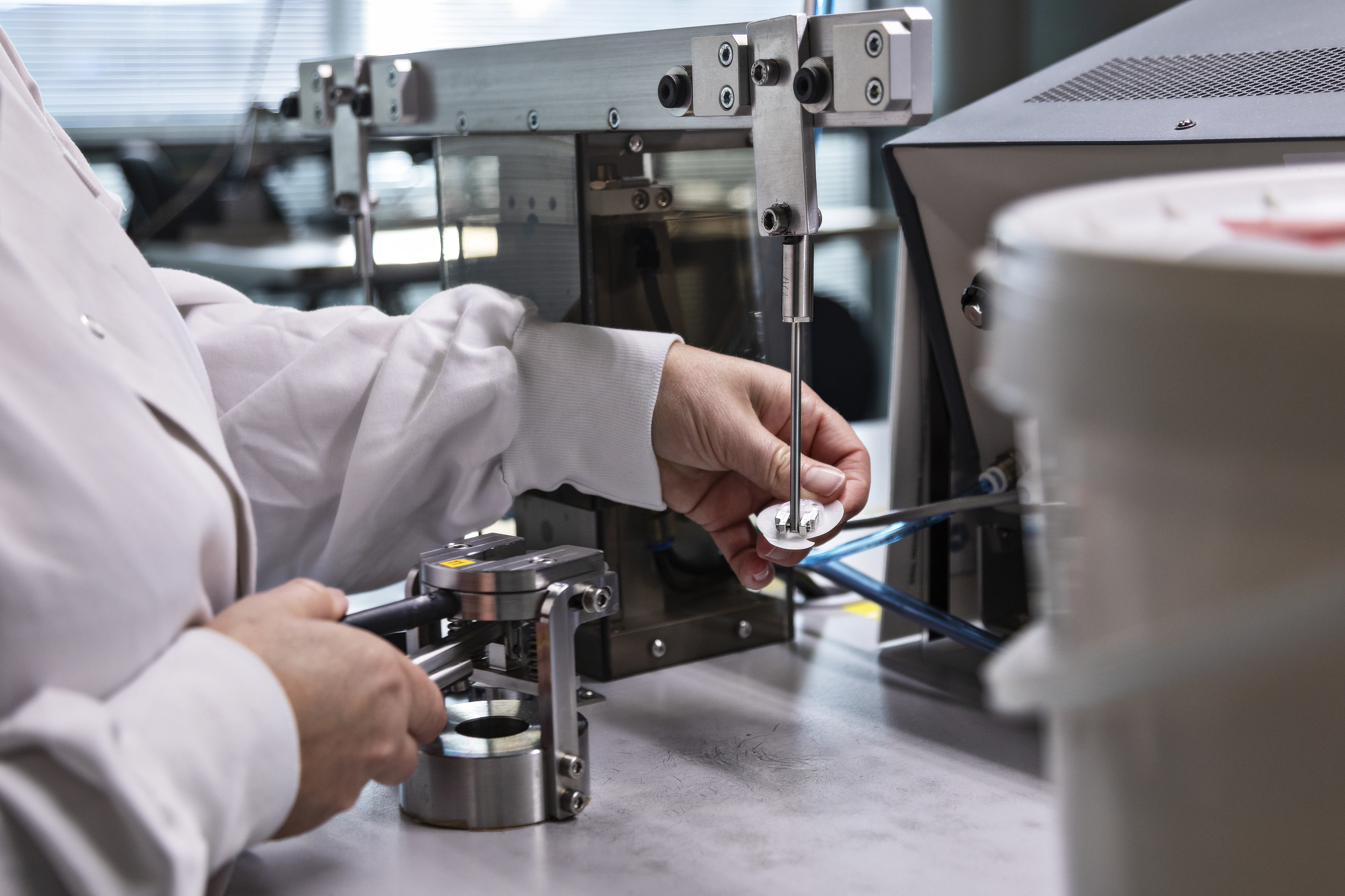 laboratoriotakkiin pukeutunut henkilö, joka työskentelee koneella